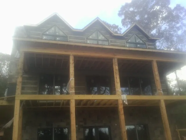Dormers and porch framing on a large log home under construction — Roof Coating work by our crew in Windsor